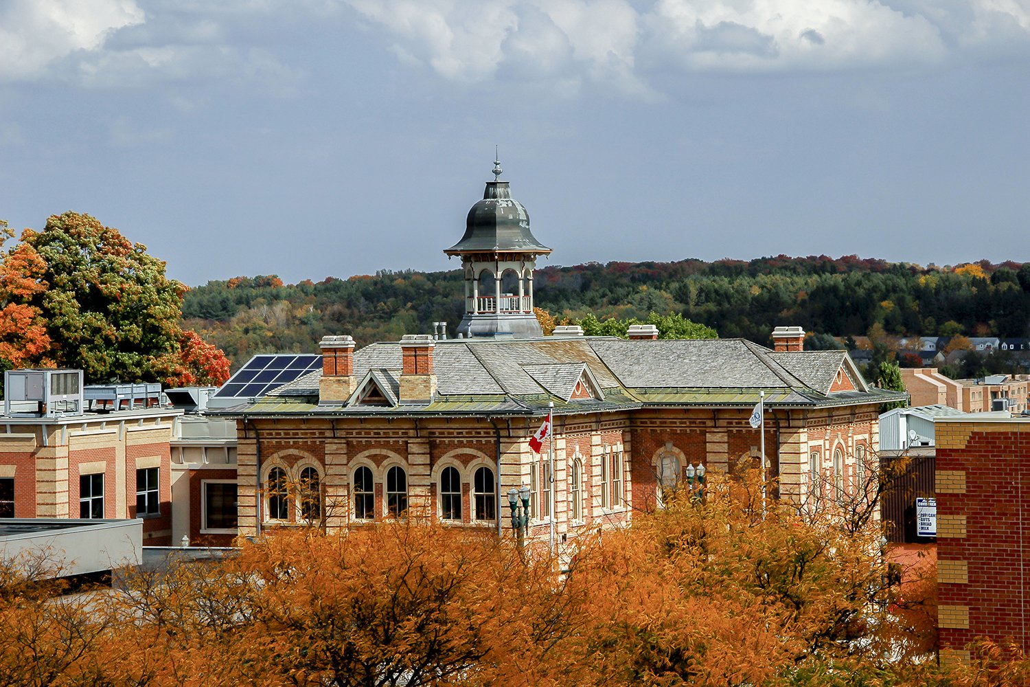 A picture of a historical building surrounded by large maple trees in the fall. An aerial shot of Orangeville's Town Hall in Orangeville, Ontario.